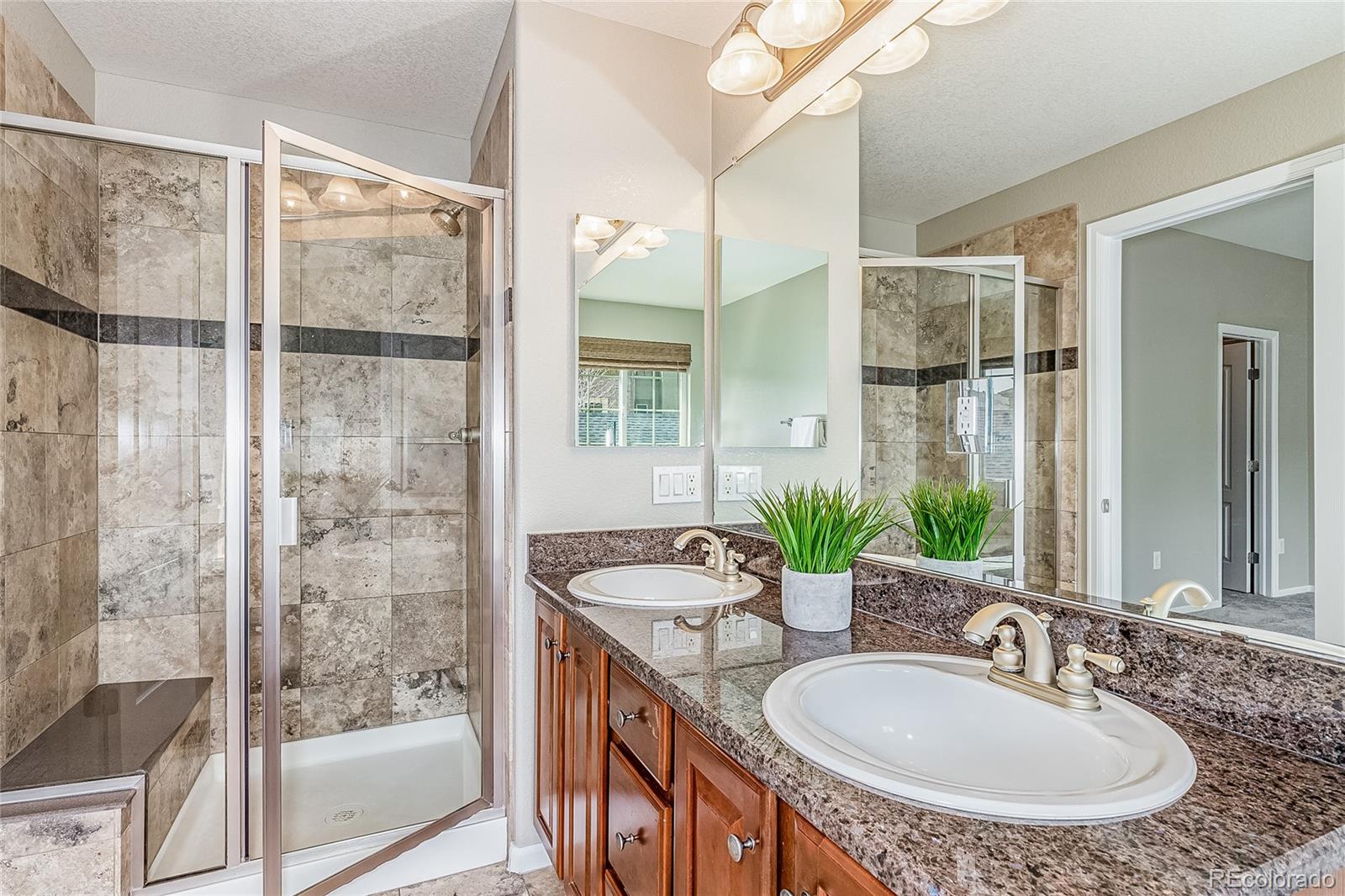 592 Brookhurst Avenue, Unit 26B Highlands Ranch, CO 80129 - Photo 16 of 19 a bathroom with a granite countertop sink a mirror and a shower