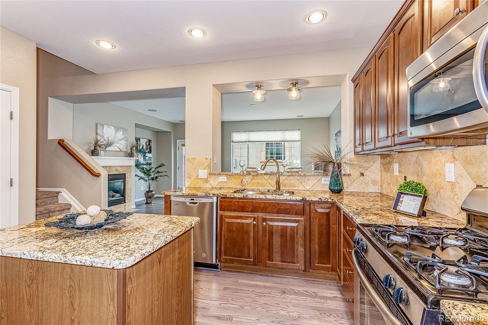 592 Brookhurst Avenue, Unit 26B Highlands Ranch, CO 80129 - Photo 3 of 19 a kitchen with stainless steel appliances granite countertop a stove top oven a sink dishwasher and cabinets with wooden floor