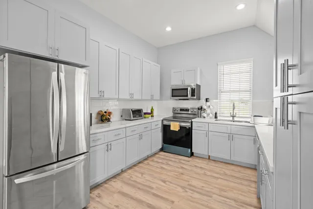 a kitchen with white cabinets stainless steel appliances and a refrigerator