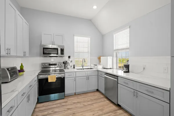 a kitchen with a sink white cabinets and white appliances
