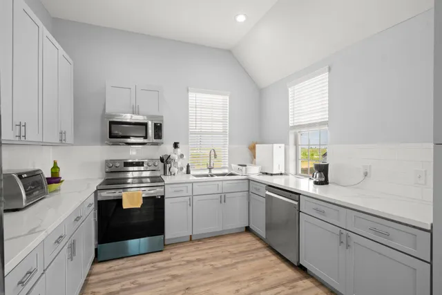 a kitchen with a sink white cabinets and white appliances