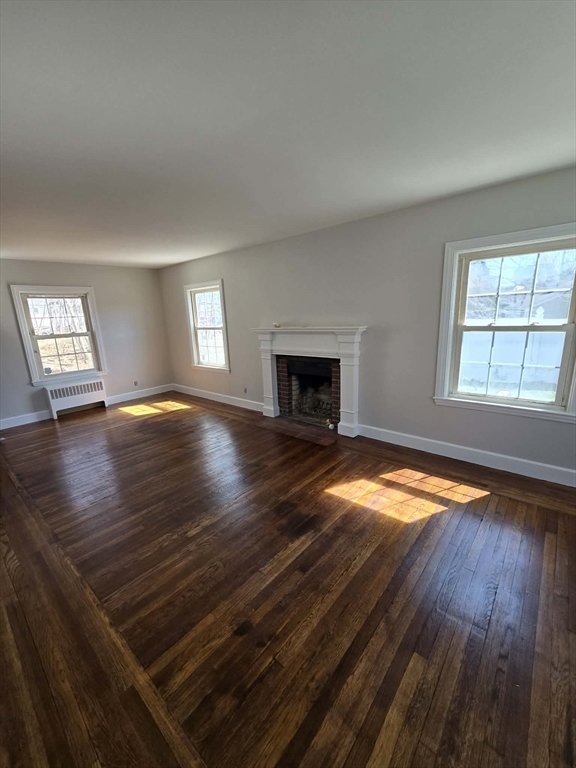 171 Mendon Road Attleboro, MA 02703 - Photo 3 of 11 an empty room with wooden floor fireplace and windows