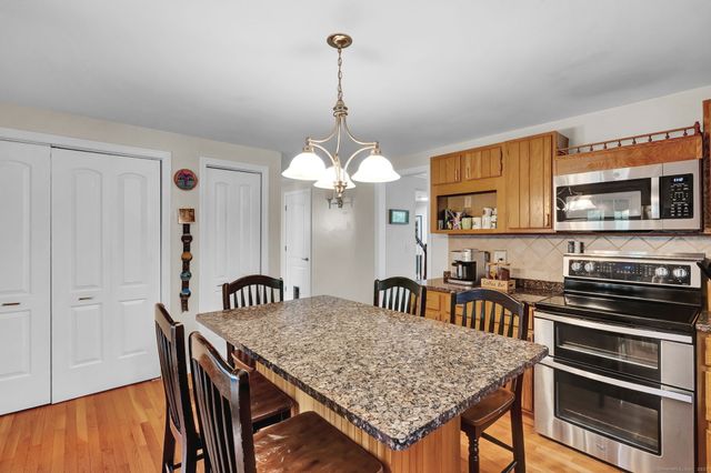 a kitchen with stainless steel appliances granite countertop a stove a kitchen island a dining table and chairs