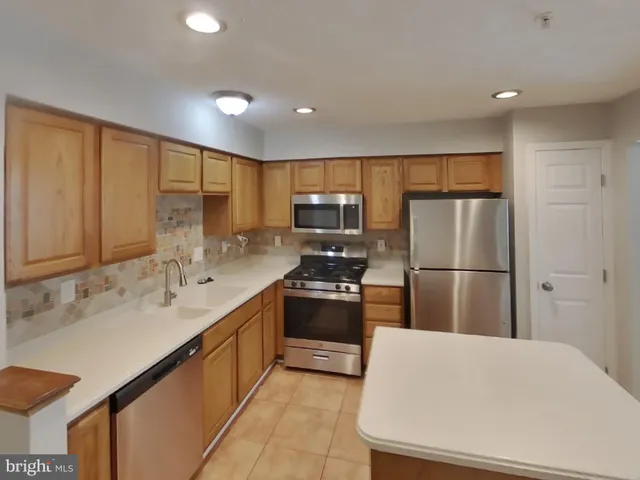 a large kitchen with stainless steel appliances granite countertop a refrigerator a sink a stove a microwave and a refrigerator