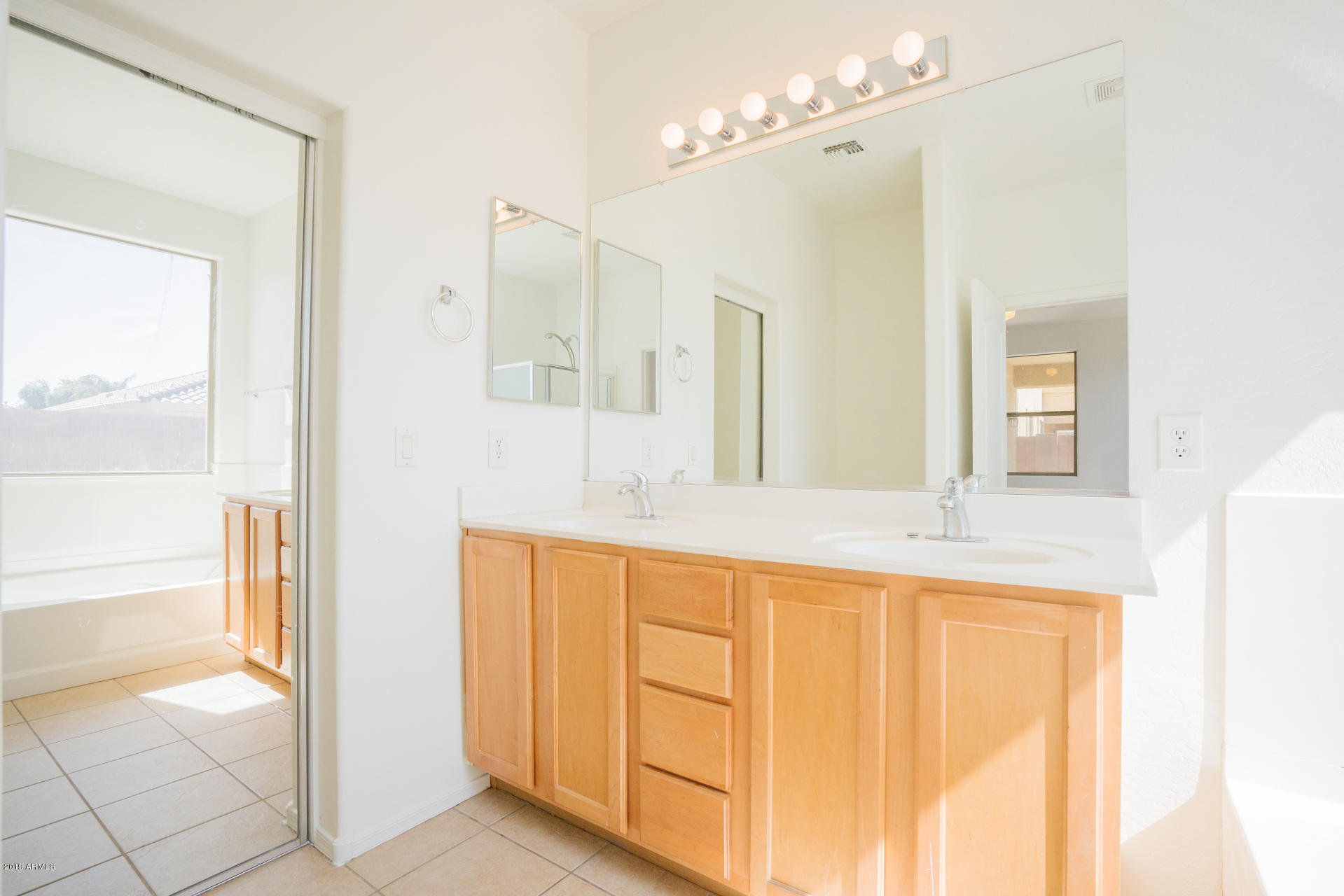 14241 West Calavar Road Surprise, AZ 85379 - Photo 5 of 26 a spacious bathroom with a granite countertop sink a mirror and a bathtub