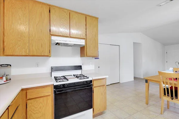 a kitchen with stainless steel appliances granite countertop a stove top oven a sink dishwasher and white cabinets with wooden floor