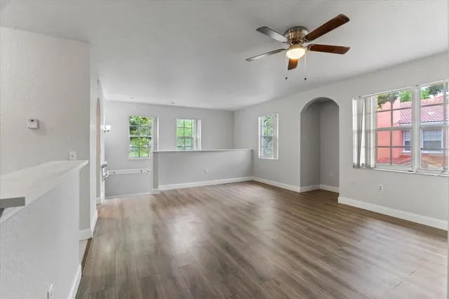 a view of an empty room with a window and wooden floor