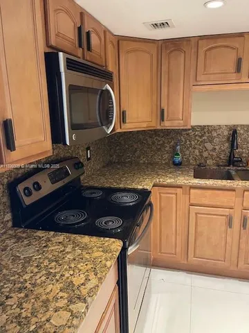 a kitchen with granite countertop a sink and a stove