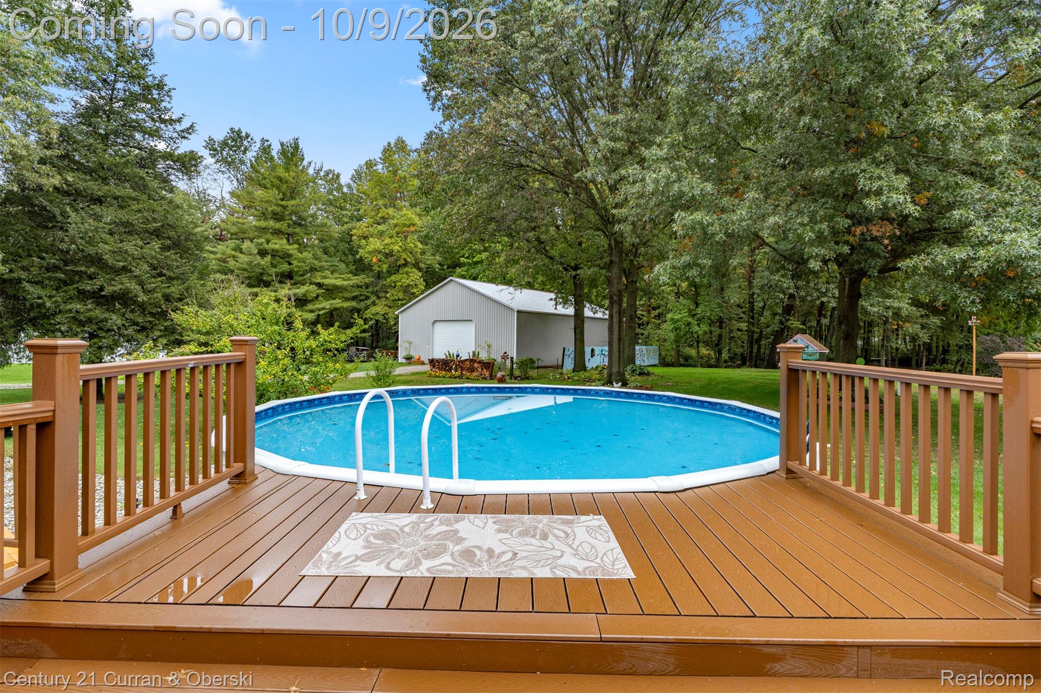 43040 Willis Road Belleville, MI 48111 - Photo 47 of 65 Spacious wood-finish deck with railings, an above-ground swimming pool, and a white storage building with a roll-up door
