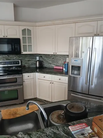 a kitchen with appliances a sink and cabinets