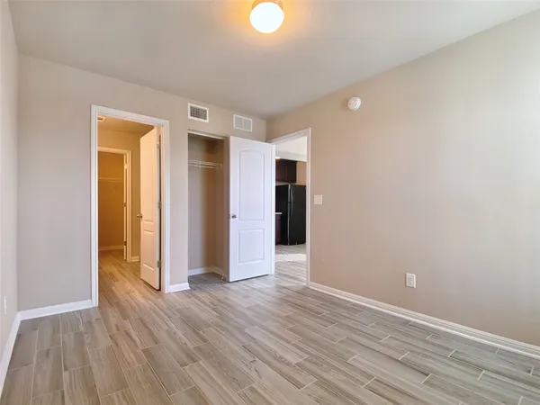 a view of an empty room with wooden floor and closet
