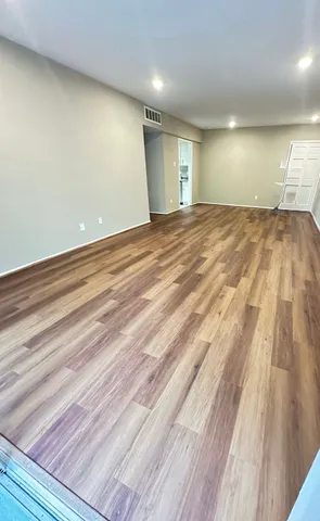 an empty room with wooden floor and windows