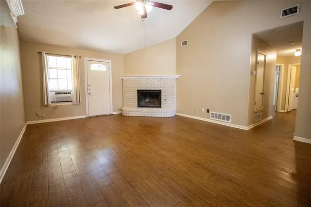 an empty room with wooden floor and fireplace