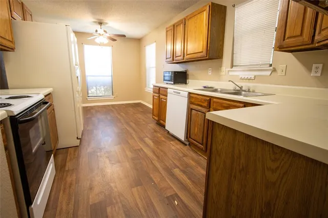 a kitchen with a sink wooden floor and a stove top oven