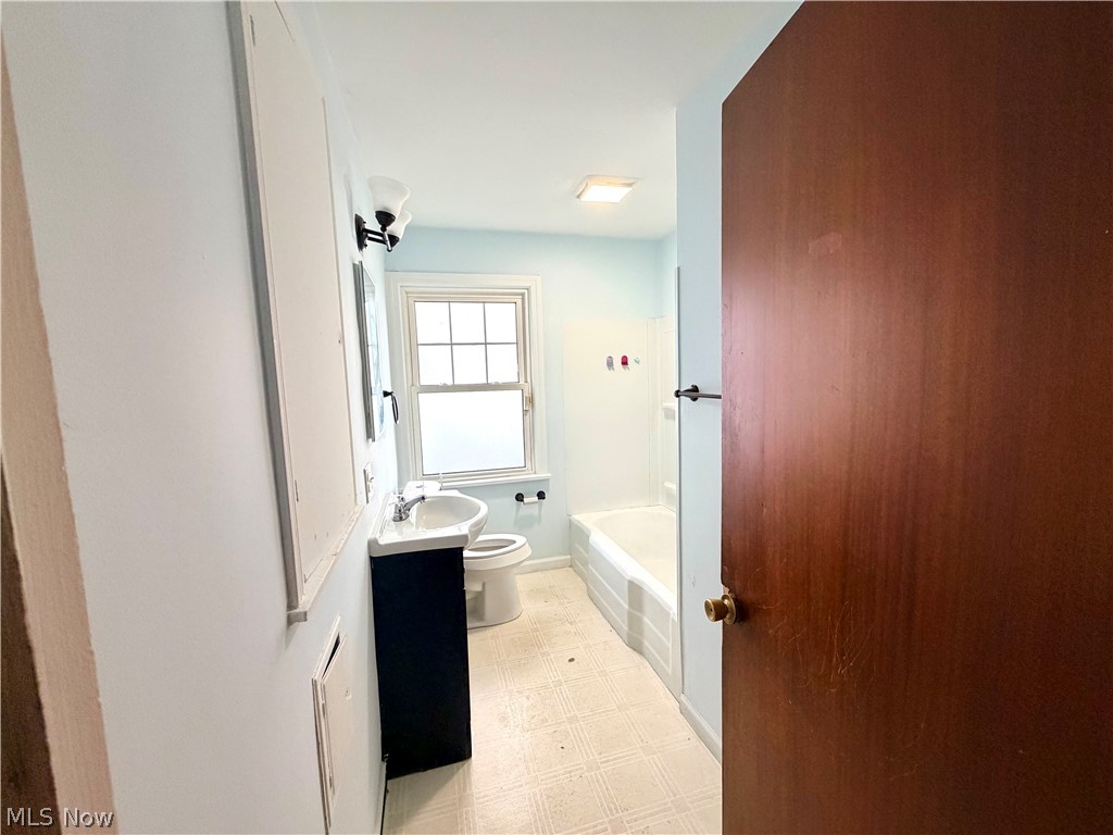 10506 Park Heights Road Cleveland, OH 44104 - Photo 12 of 22 Full bathroom featuring a window, white bathtub, vanity with integrated sink, and overhead lighting