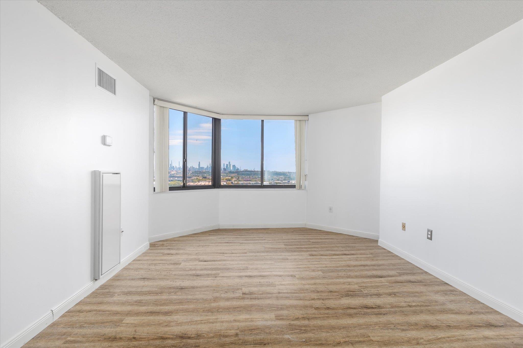 1705 Harmon Cove Tower, Unit 1705 Secaucus, NJ 07094 - Photo 24 of 49 an empty room with wooden floor and windows