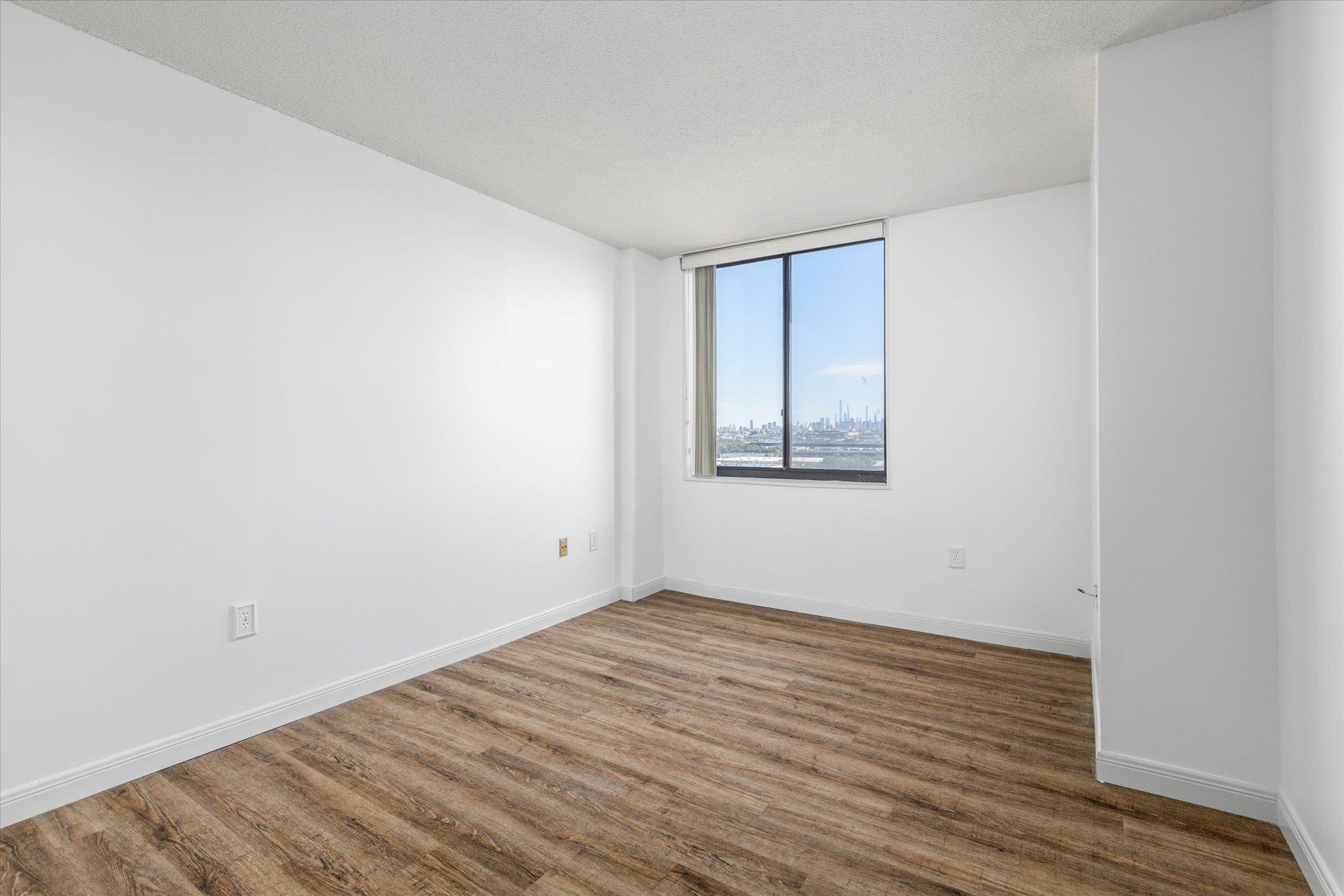 1705 Harmon Cove Tower, Unit 1705 Secaucus, NJ 07094 - Photo 30 of 49 an empty room with wooden floor and windows