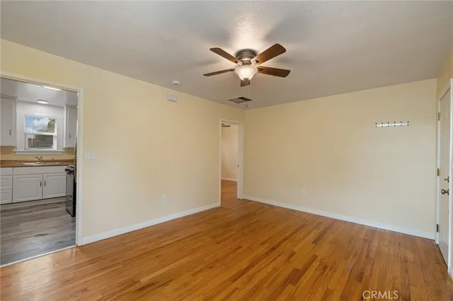 a view of a room with wooden floor and a ceiling fan