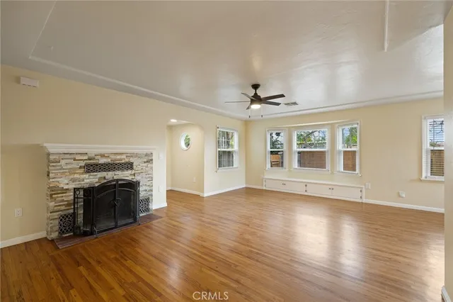 an empty room with wooden floor fireplace and windows