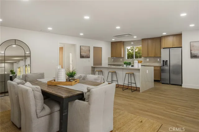 a kitchen with stainless steel appliances granite countertop a table chairs refrigerator and sink