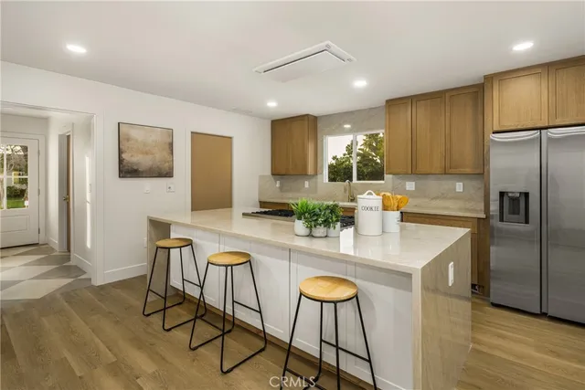 a kitchen with stainless steel appliances granite countertop a sink a stove a refrigerator cabinets and chairs