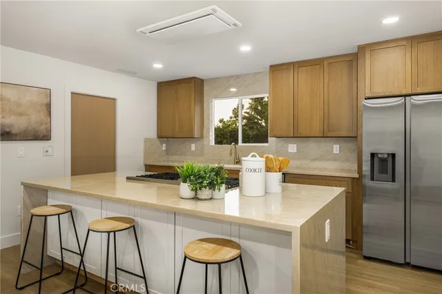 a kitchen with stainless steel appliances granite countertop a kitchen island a stove a microwave a sink and a refrigerator