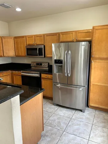 a kitchen with stainless steel appliances granite countertop a refrigerator a stove a sink and a microwave