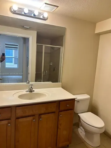 a bathroom with a granite countertop sink a toilet and a mirror