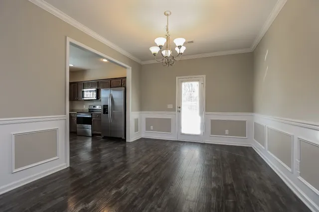 a view of a hallway with wooden floor and a kitchen