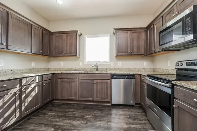 a kitchen with stainless steel appliances granite countertop a sink a stove a microwave and cabinets
