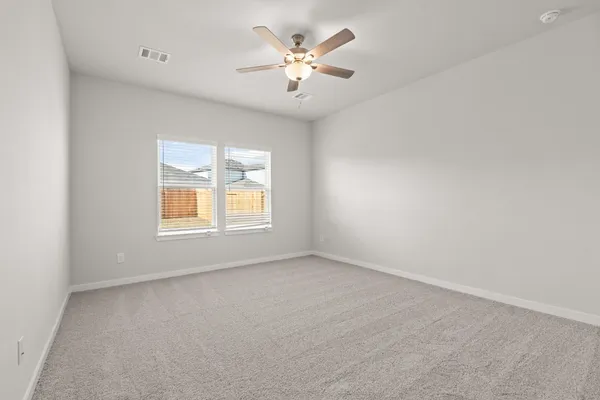 an empty room with windows and chandelier fan