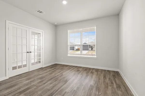 an empty room with wooden floor and windows