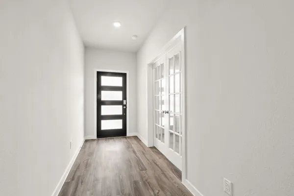 an empty room with wooden floor and windows