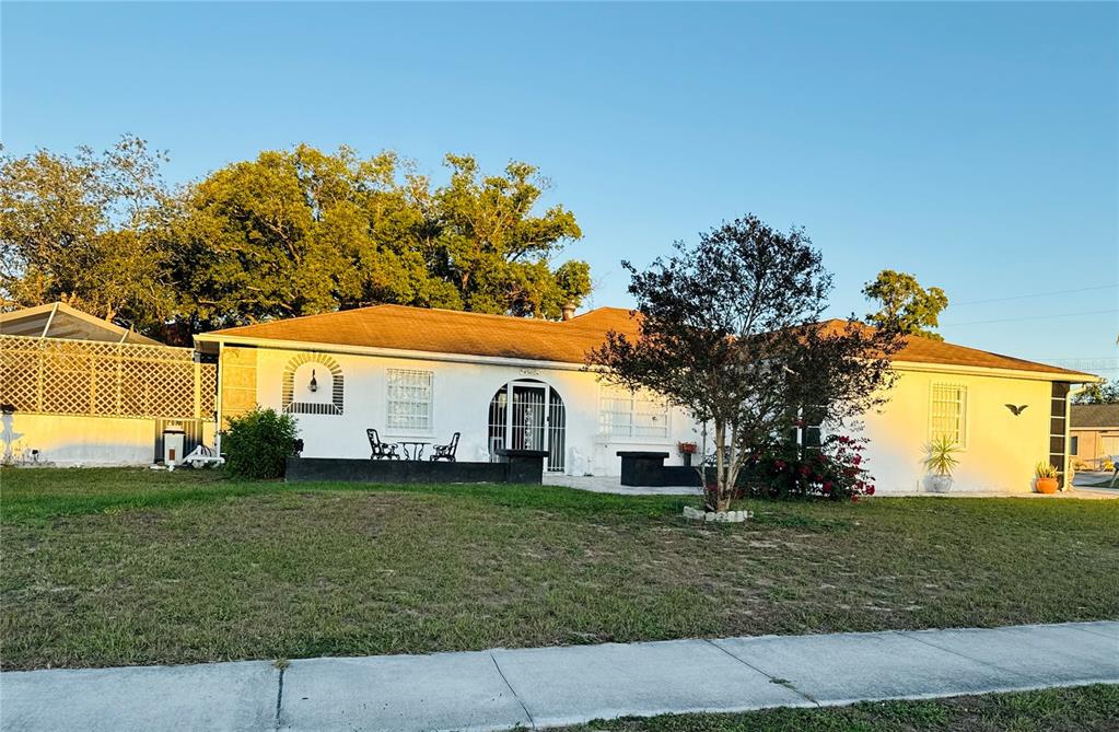 a view of a white house next to a yard with big trees