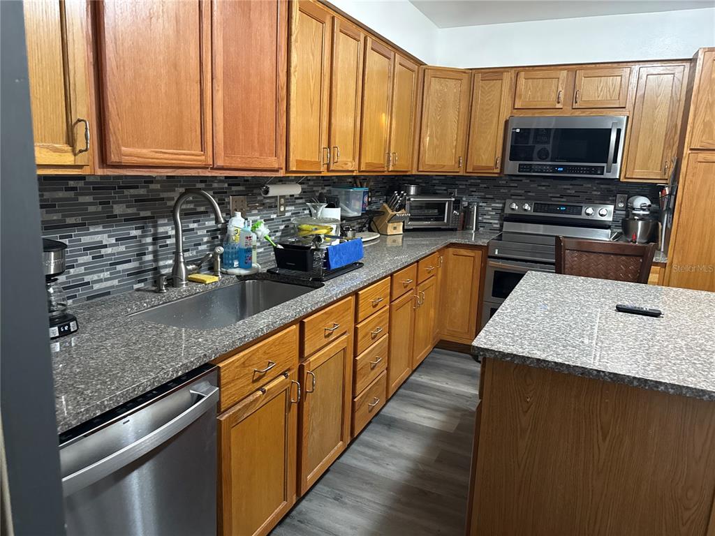 4560 Lamson Avenue Spring Hill, FL 34608 - Photo 20 of 41 a kitchen with stainless steel appliances granite countertop a stove a sink and a microwave