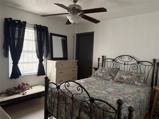 a bedroom with a bed a dresser and potted plants
