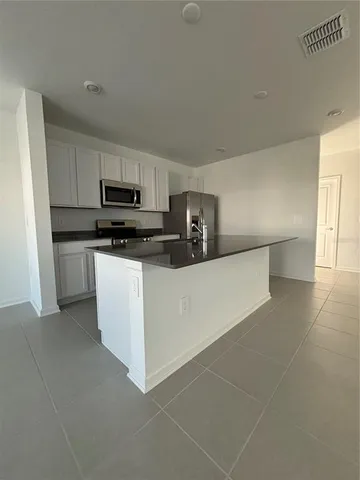 a kitchen with stainless steel appliances a sink a stove a microwave a sink a refrigerator and cabinets