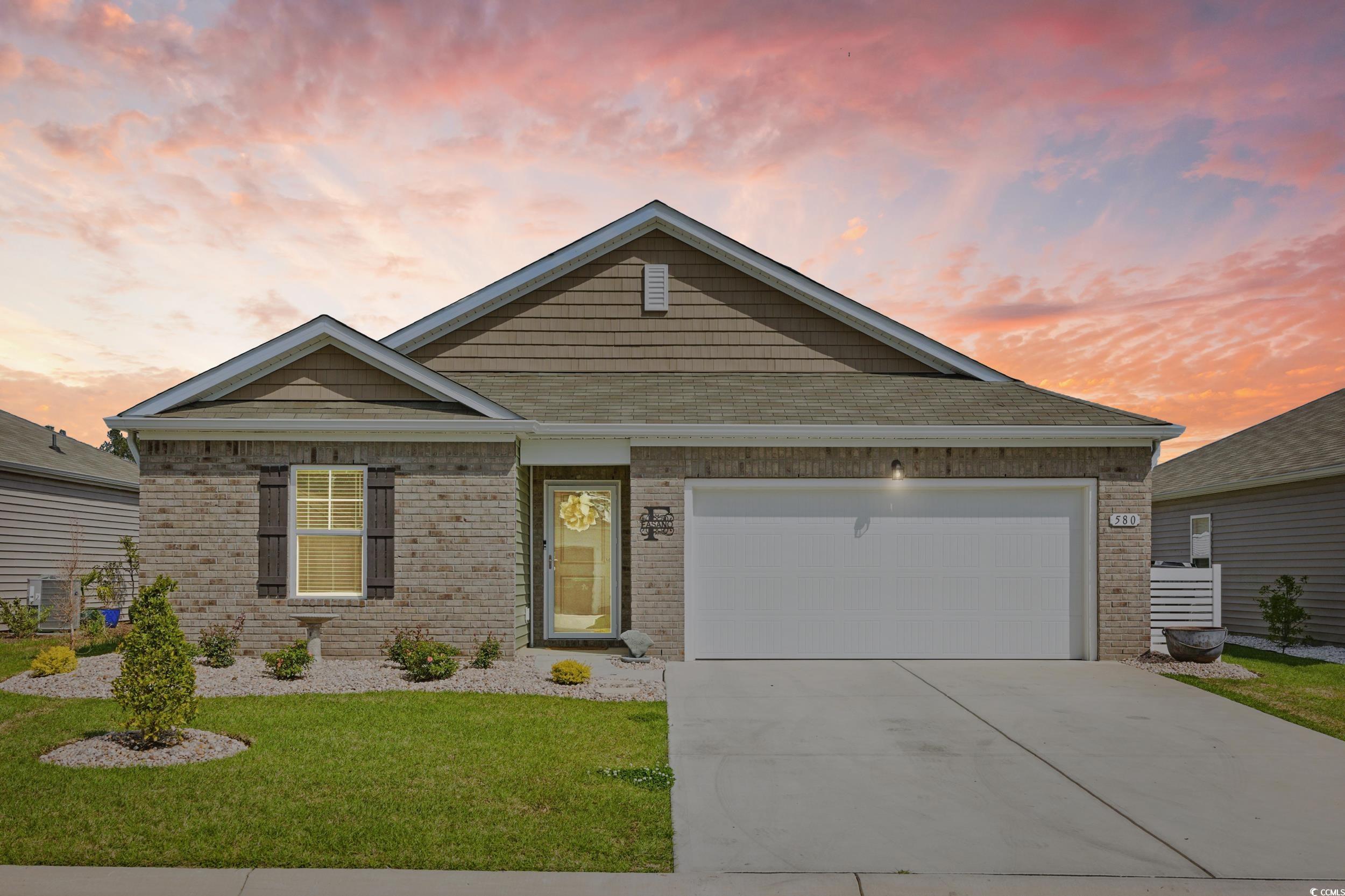 View of front of property with brick siding, concrete driveway, a front yard, and an attached garage