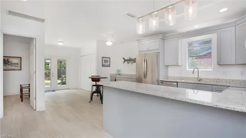 a view of a kitchen with kitchen island a sink appliances wooden floor and a window