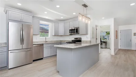 a kitchen with kitchen island a counter top space stainless steel appliances and a window