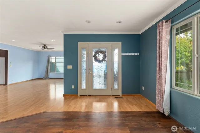 a view of an empty room with window and wooden floor