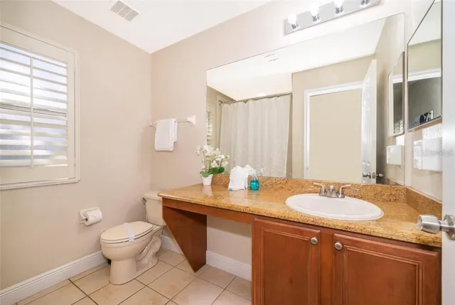 a bathroom with a granite countertop sink a toilet and a mirror