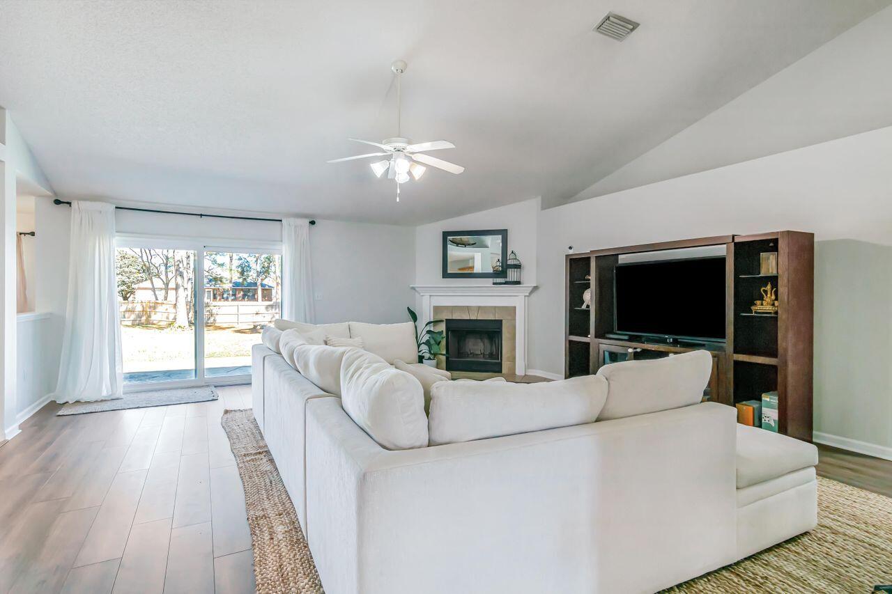 6830 Fernandina Road Navarre, FL 32566 - Photo 9 of 37 a living room with furniture a flat screen tv and a fireplace