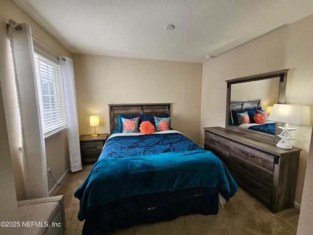 a bedroom with a bed and a mirror on dresser