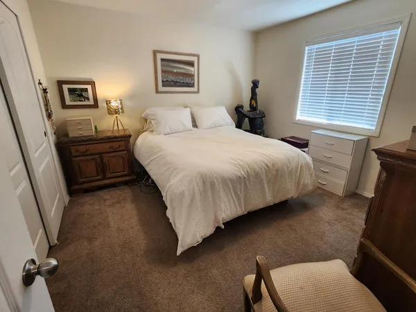 a bedroom with a bed a painting on the wall and a window