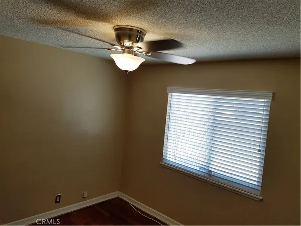 a view of a room with a hanging light and hardwood floor