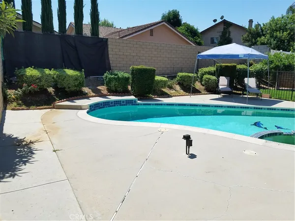 a backyard of a house with table and chairs under an umbrella