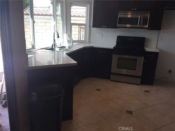 a kitchen with granite countertop a stove a sink and a microwave