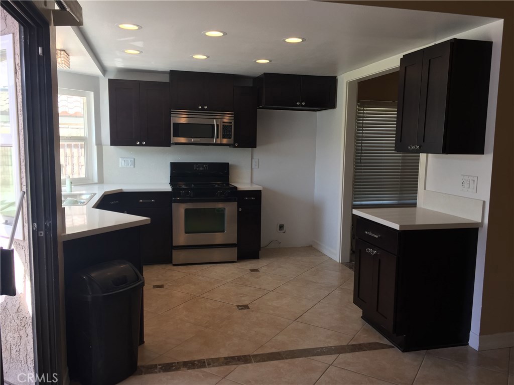 50 Village Loop Road Phillips Ranch, CA 91766 - Photo 8 of 48 a kitchen with stainless steel appliances granite countertop a refrigerator a stove a microwave oven and a sink with wooden cabinets