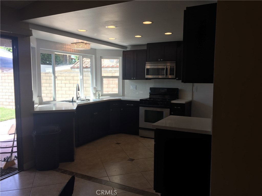 50 Village Loop Road Phillips Ranch, CA 91766 - Photo 10 of 48 a kitchen with a sink wooden cabinets and black appliances